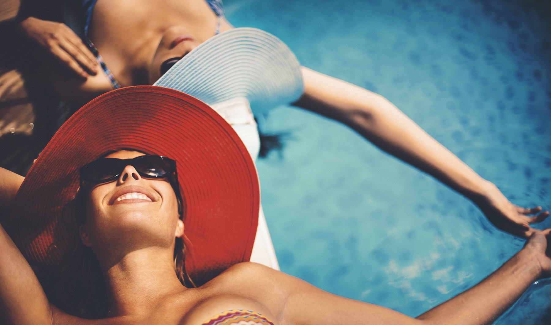 Swimming Pool  Friends laying out on a float in a sparkling blue pool